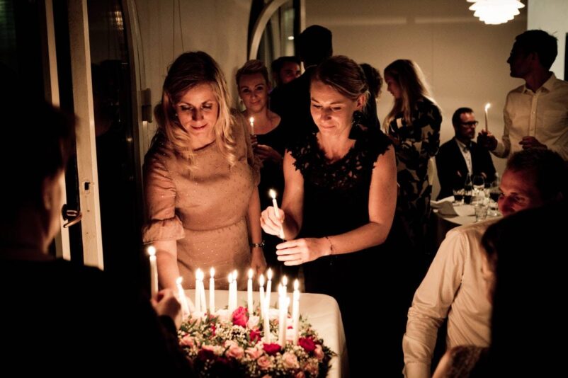 Two women holding candles at a party - GIB exchange scam alert